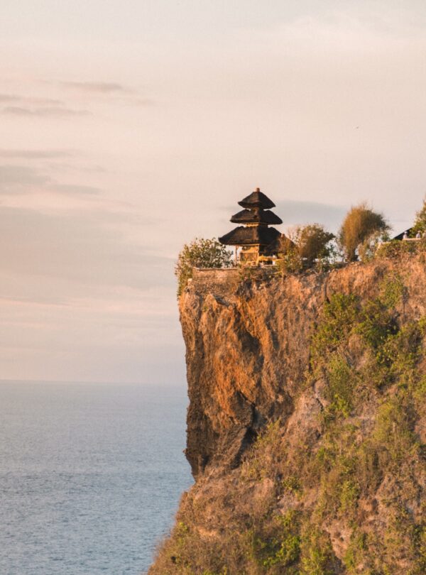 brown wooden house on brown rock formation near body of water during daytime